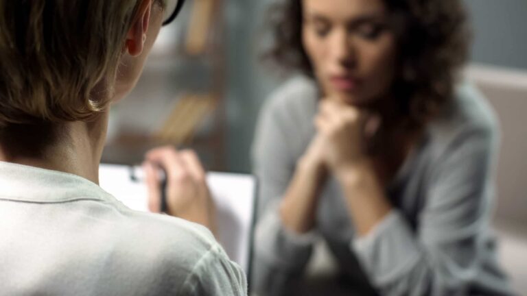 Young depressed woman talking to lady psychologist during session